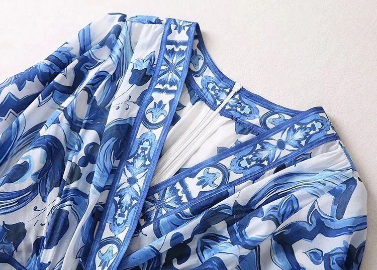 Blue floral-patterned chiffon dress with intricate detailing and stylish neckline. Perfect for summer occasions.