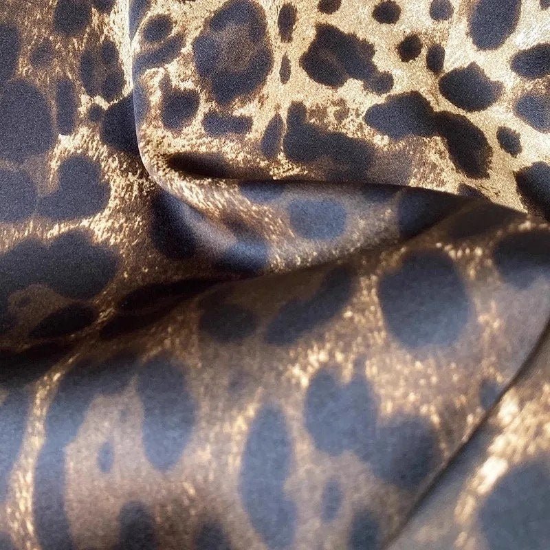 Brown and gold leopard print satin fabric, ideal for stylish apparel and accessories.