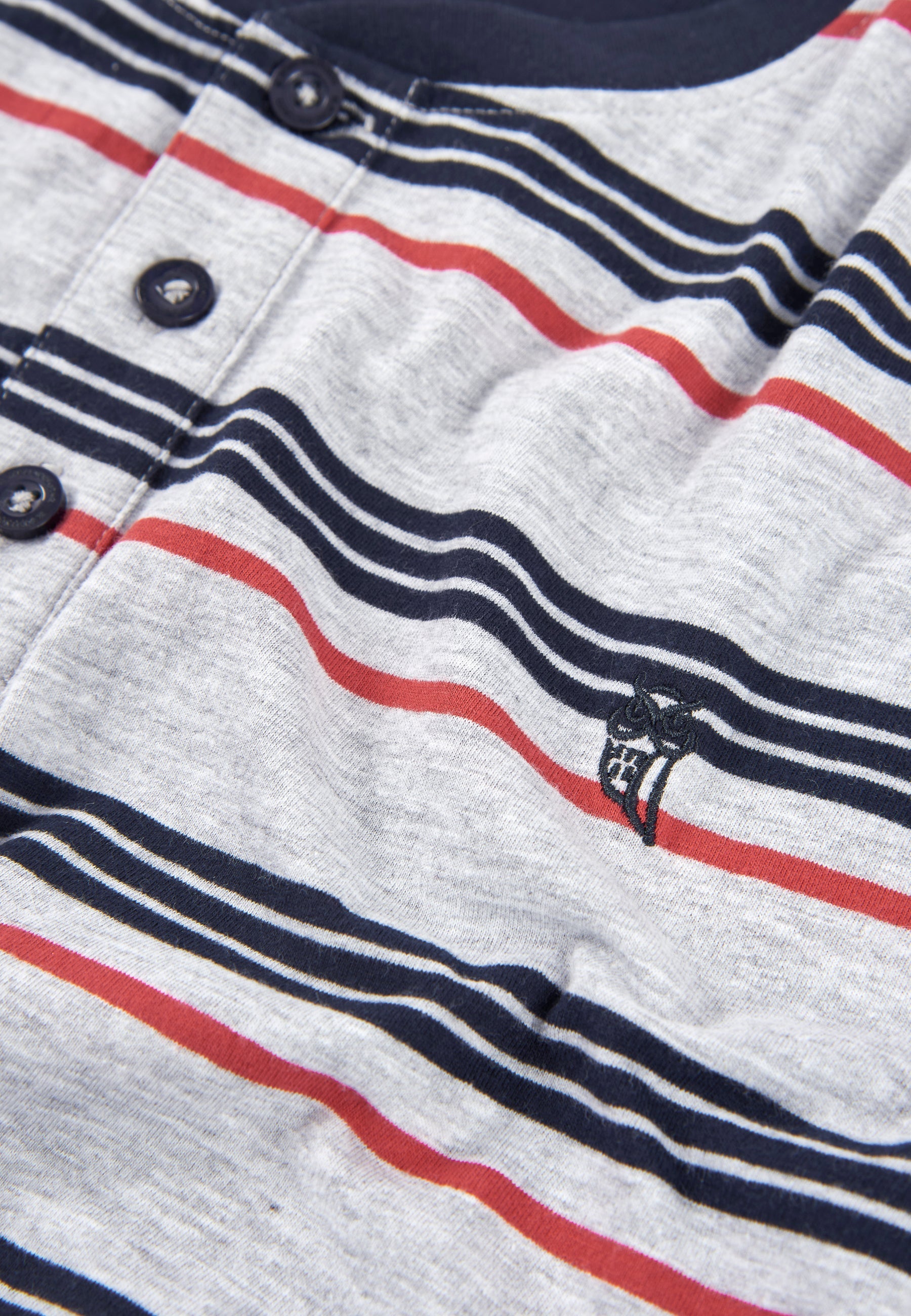 Camiseta de rayas gris con botones, detalles en azul marino y rojo, estilo casual de algodón.