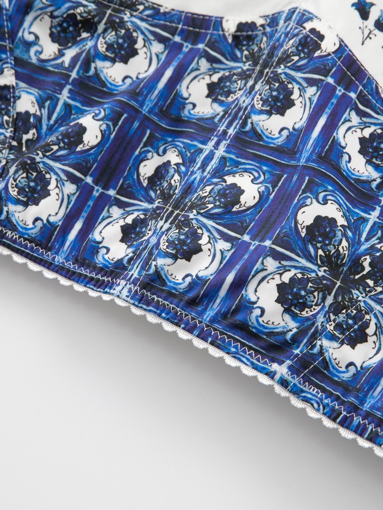 Blue and white cotton top featuring a tiled Majolica print with decorative white scalloped lace trim.