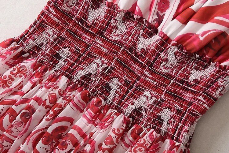 Red floral smocked dress with intricate patterns and a flowing skirt made of lightweight fabric. Perfect for summer outings.