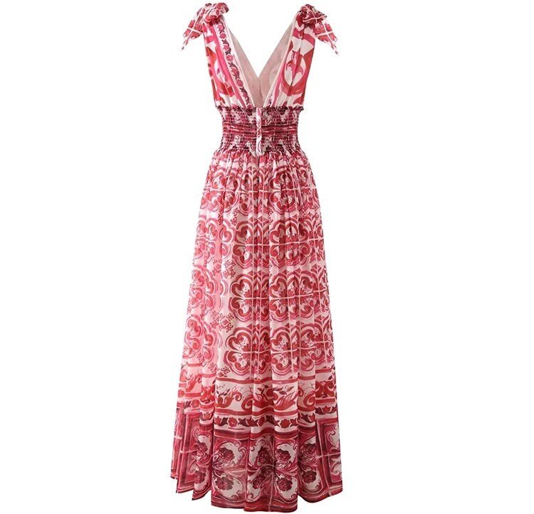 Pink bohemian maxi dress with smocked waist and tie straps, featuring intricate floral patterns in flowing fabric.