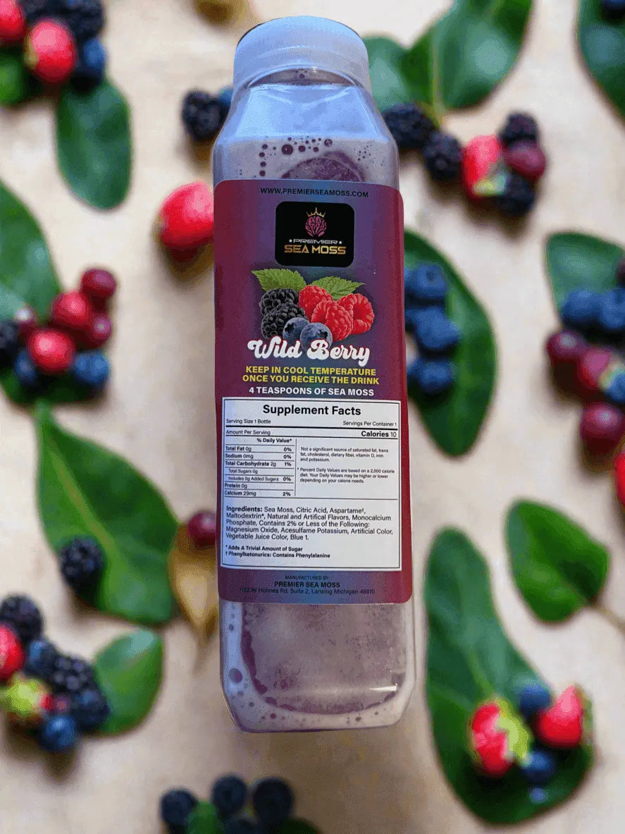 12 oz. Wild Berry Sea Moss drink in a clear plastic bottle, surrounded by scattered berries and green leaves.