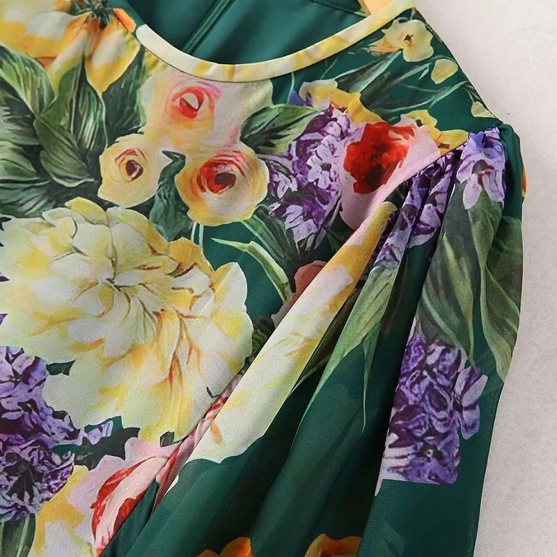 Floral print blouse featuring vibrant yellow, pink, and purple flowers on a green background, made from lightweight fabric.