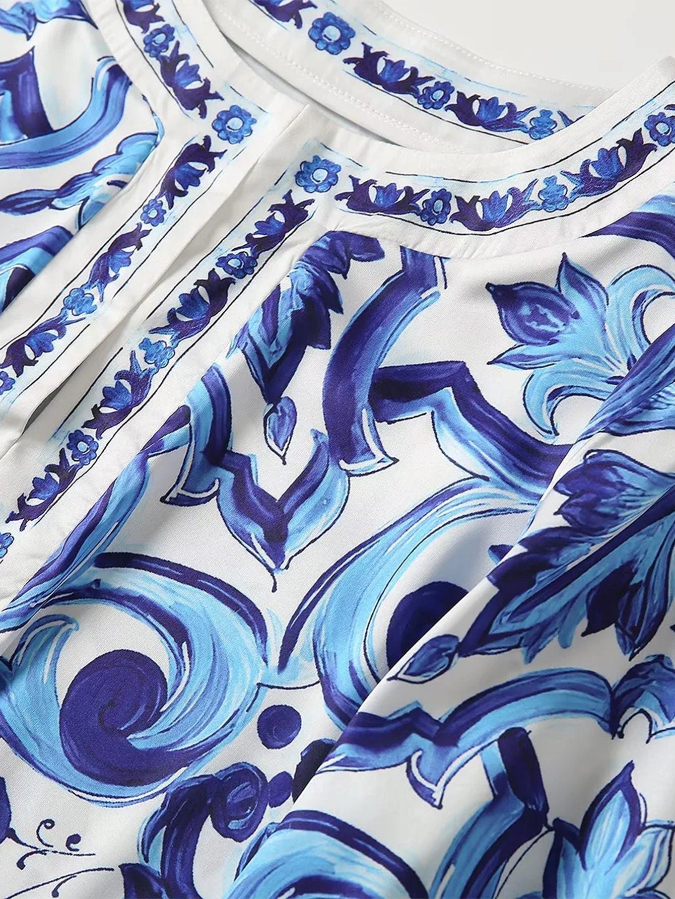 Blue and white floral print blouse with intricate design and button details, perfect for casual or semi-formal wear.