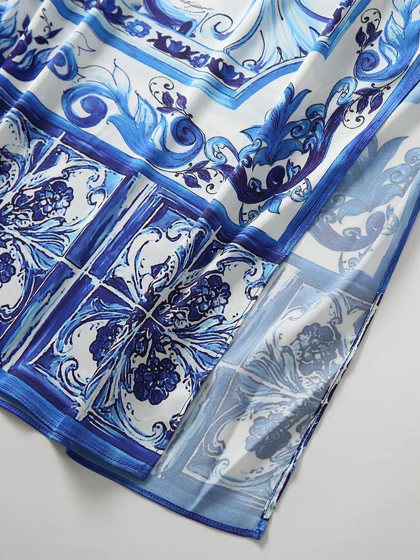 Blue and white patterned silk scarf with ornate designs, perfect for a chic and stylish accessory.