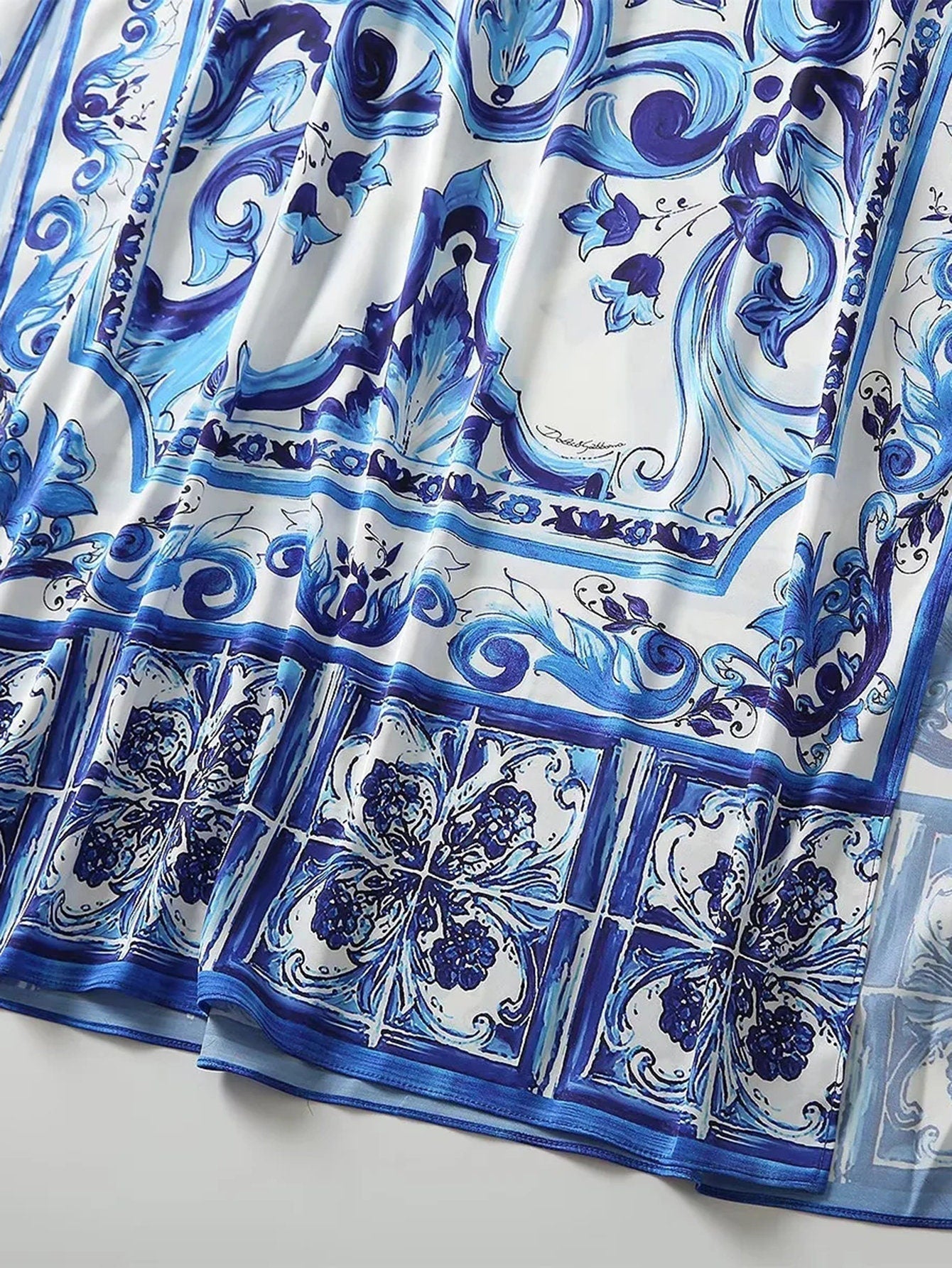 Blue and white patterned silk scarf featuring intricate floral designs and elegant baroque motifs.