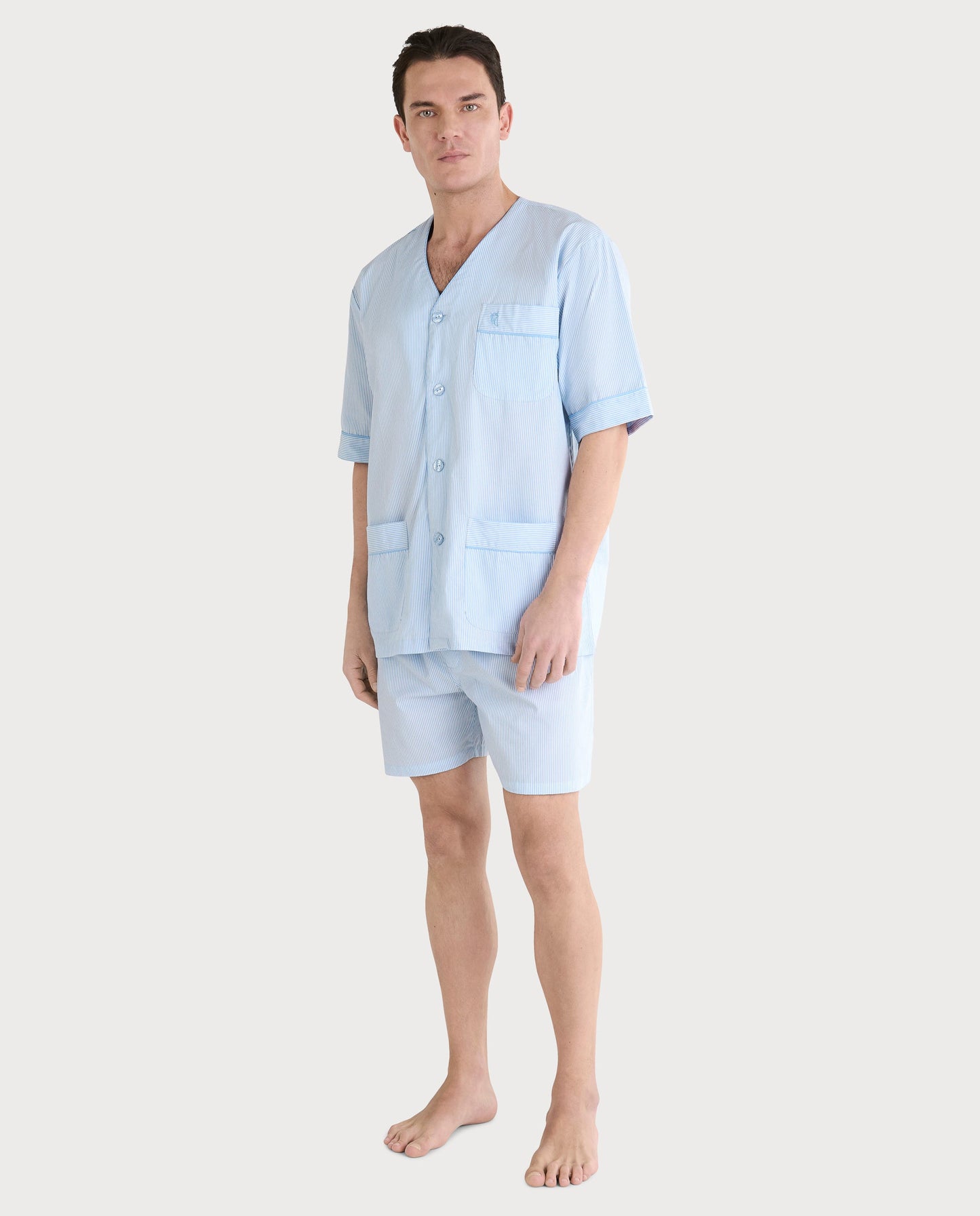 Pijama de hombre de rayas azules, material ligero, con camisa de botones y pantalones cortos, estilo casual y cómodo.