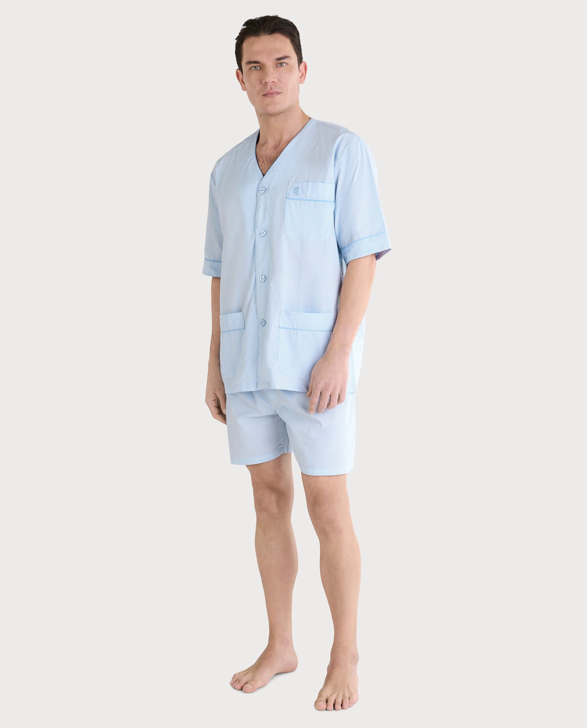 Pijama de hombre de rayas azules, material ligero, con camisa de botones y pantalones cortos, estilo casual y cómodo.