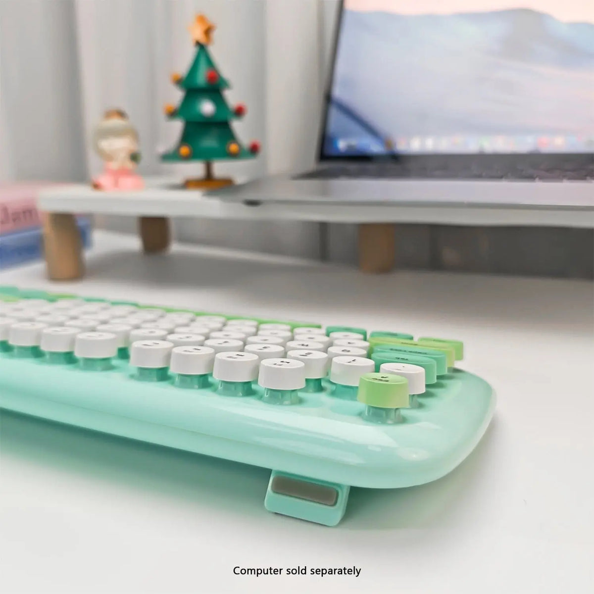 Mint green wireless keyboard with 104 retro-style round white keys on a white desk with a laptop stand.