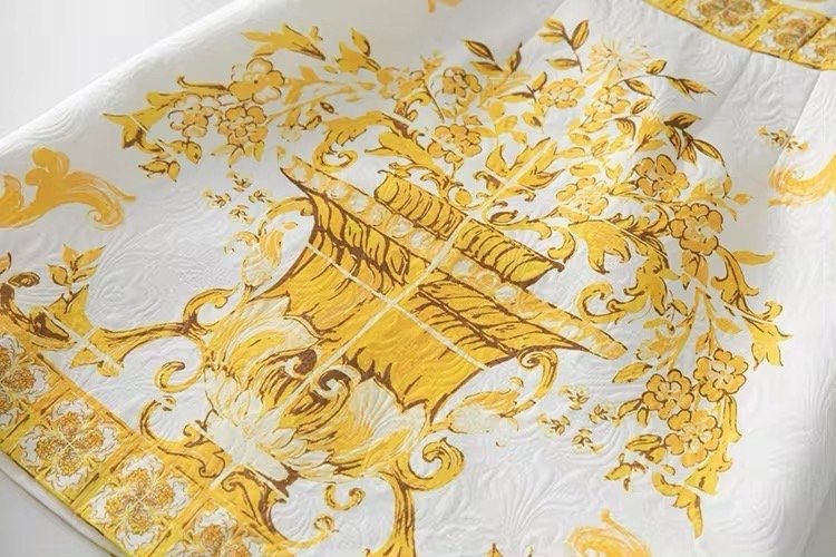 Elegant white and gold floral-patterned tablecloth in luxurious fabric, perfect for upscale dining and decor.