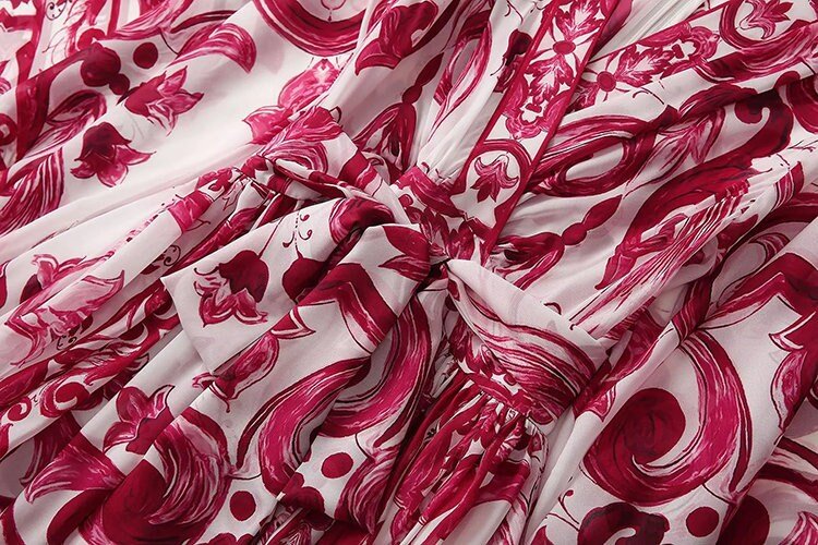 Red and white floral print dress with a cinched waist and flowing fabric, perfect for summer events.