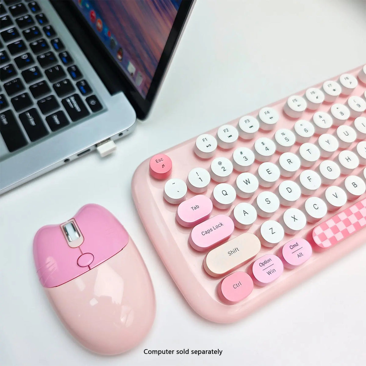 Pink wireless keyboard with round typewriter-style keys and a matching cat-shaped mouse on a white desk.