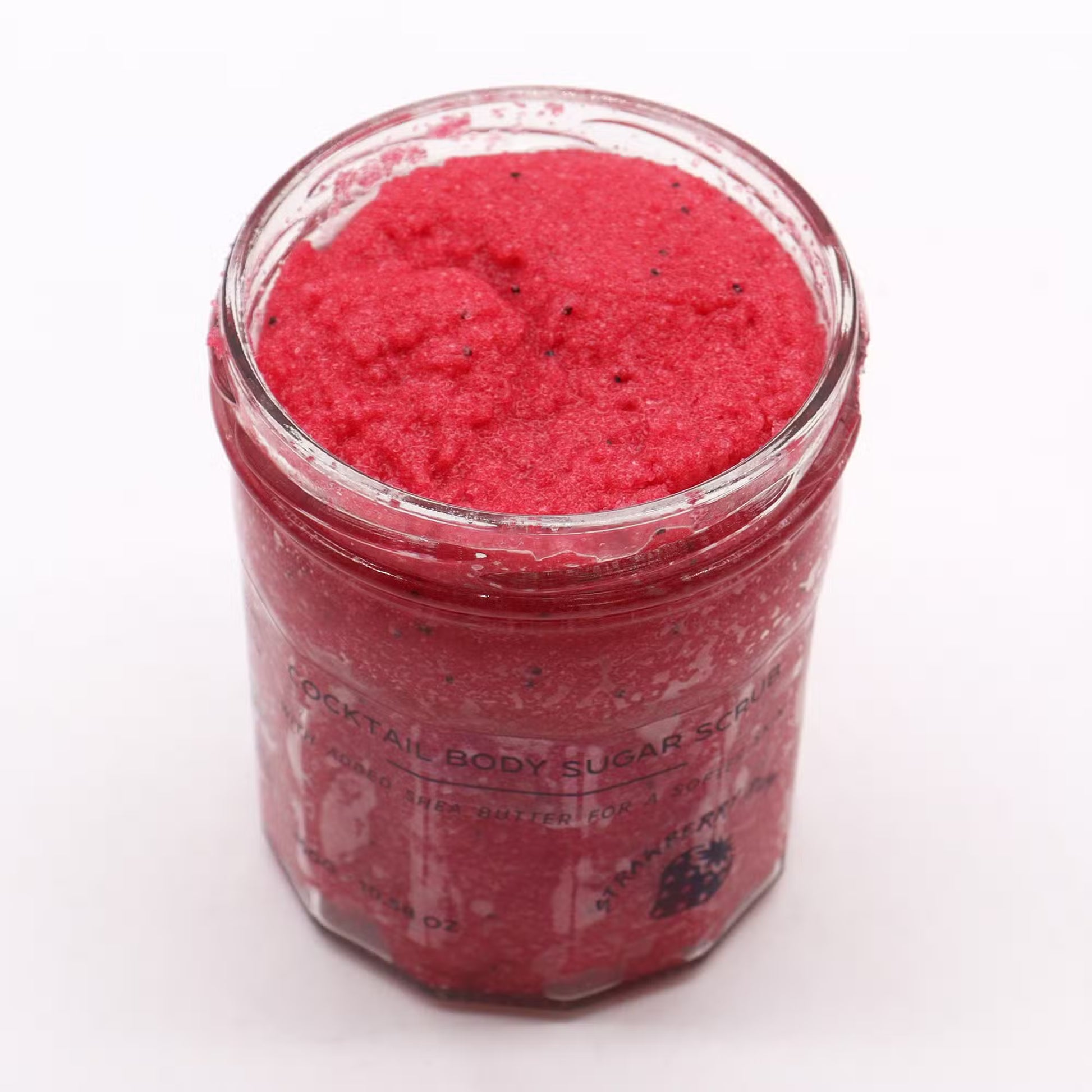 Tarro de vidrio con exfoliante corporal de azúcar rojo brillante con semillas, de textura granulada y aroma a fresa.