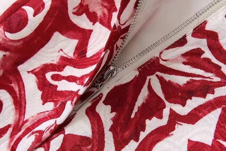 Red and white floral patterned fabric close-up with a zipper detail, perfect for stylish apparel or home decor.