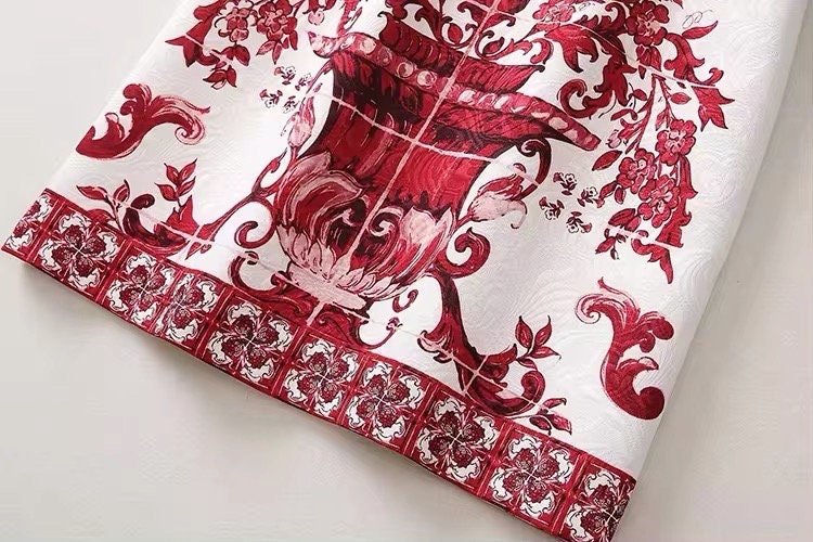 Red and white floral patterned tablecloth, featuring a classic vase design and intricate borders. Elegant dining decor.