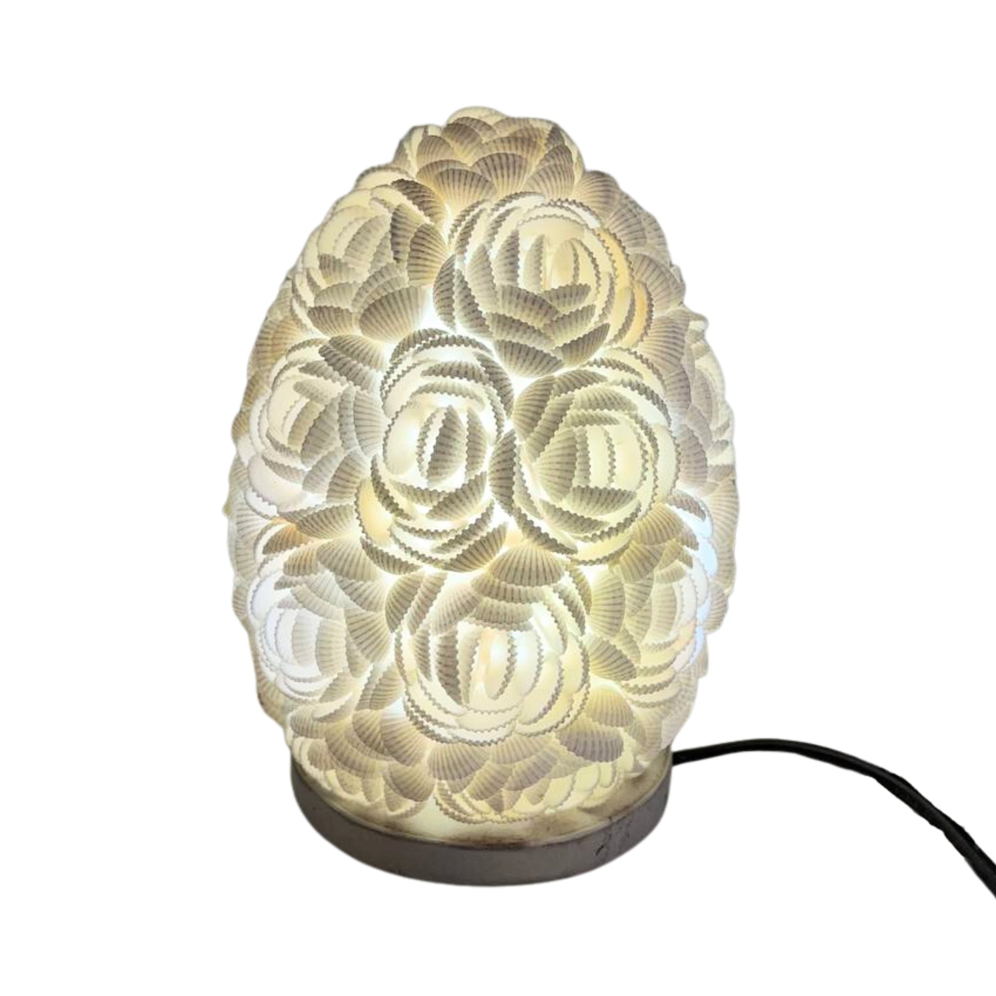 Lámpara boho ovalada de 15 cm hecha a mano con conchas marinas blancas, emitiendo una luz cálida y decorativa.