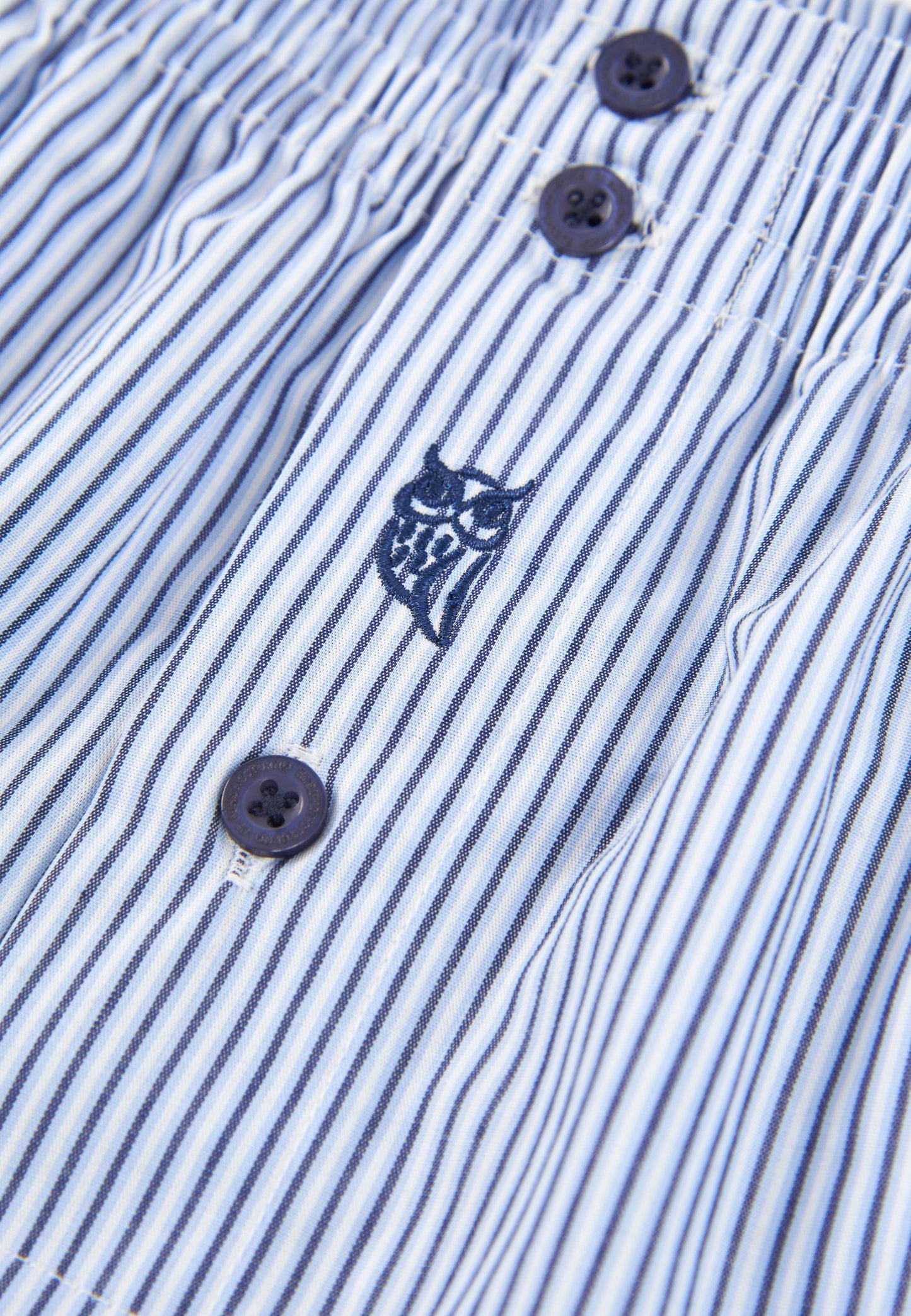 Falda de rayas azul y blanco con botones oscuros y bordado de búho en el frente, estilo veraniego.