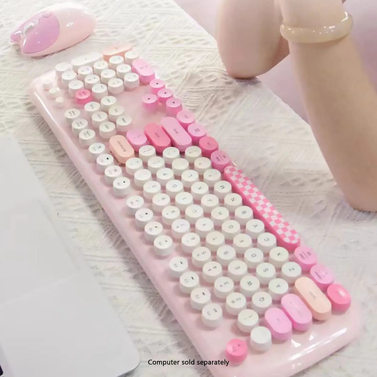 Pink and white wireless keyboard and mouse set featuring retro round typewriter-style keys on a textured fabric surface.