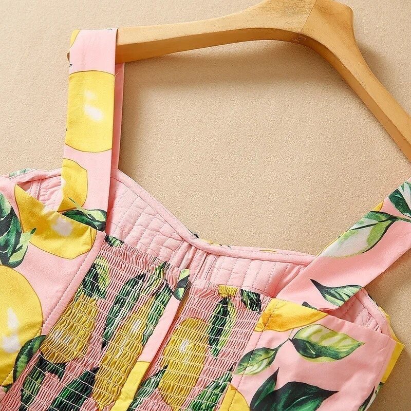 Pink lemon-print dress with smocked bodice and wide straps, perfect for summer outings.