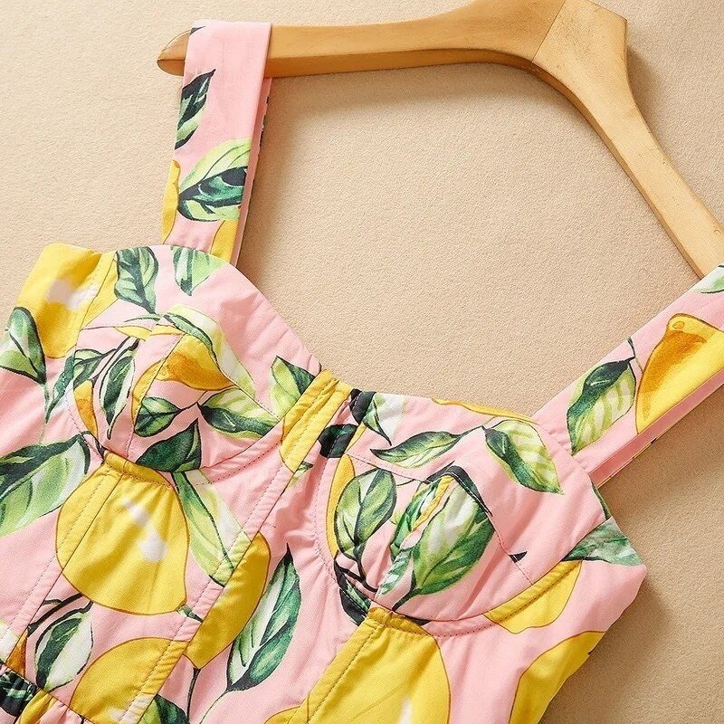 Pink lemon print dress with green leaves, featuring adjustable straps and a fitted bodice, perfect for summer.