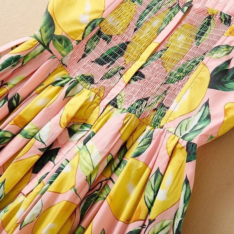 Pink lemon print dress with smocking detail and leafy design, perfect for summer outings.
