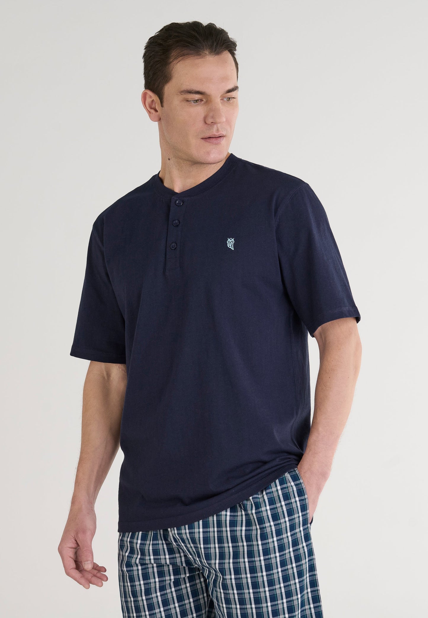 Camiseta de hombre azul marino de algodón con botones y logo, ideal para pijama, combinada con pantalones cuadros.