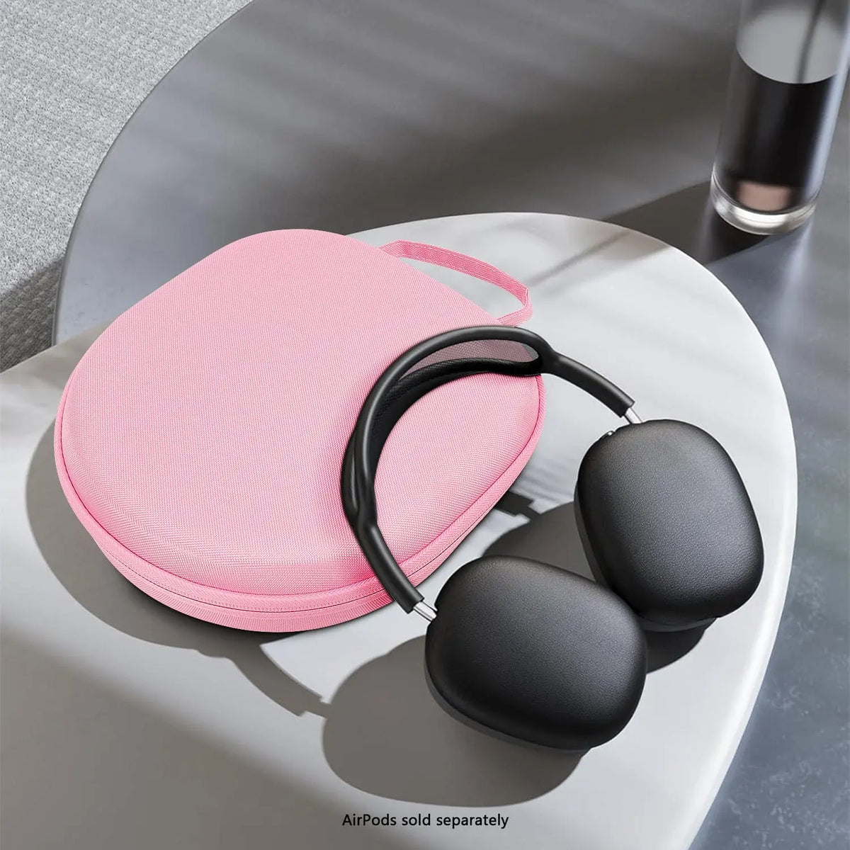 Pink hard-shell travel case for over-ear headphones with a carrying strap, shown on a white table.