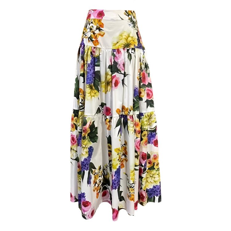 White cotton maxi skirt featuring a vibrant, multi-colored layered floral print with a flowy, tiered silhouette.