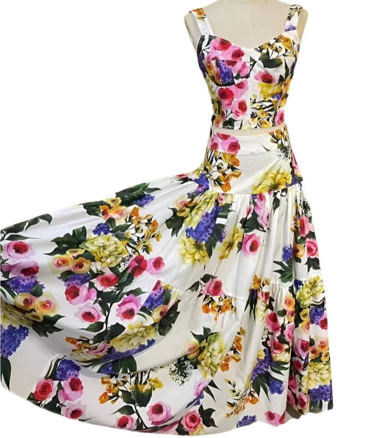 White cotton two-piece set featuring a bustier crop top and a tiered maxi skirt with a vibrant multi-floral print.