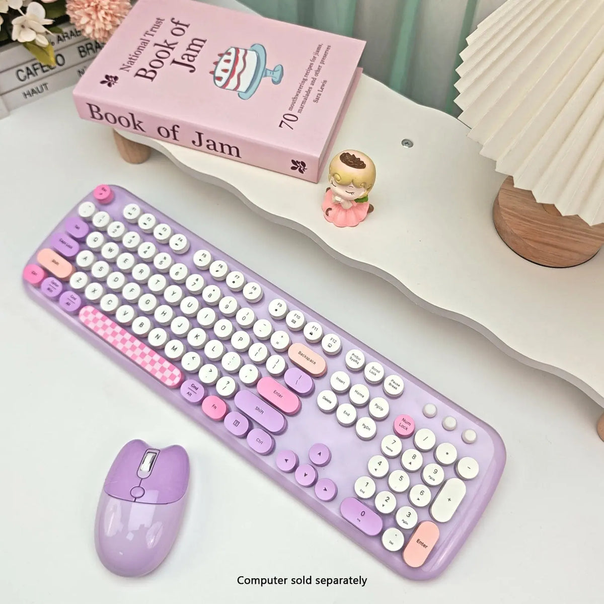 Pastel purple and pink wireless keyboard and mouse set with 104 round, typewriter-style keys on a white desk.
