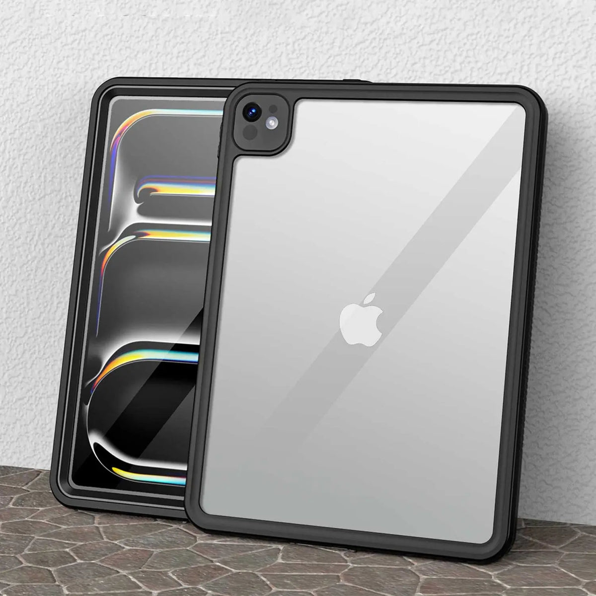 Black rugged waterproof iPad Pro case with a clear back, showing an Apple logo, standing against a stone wall.