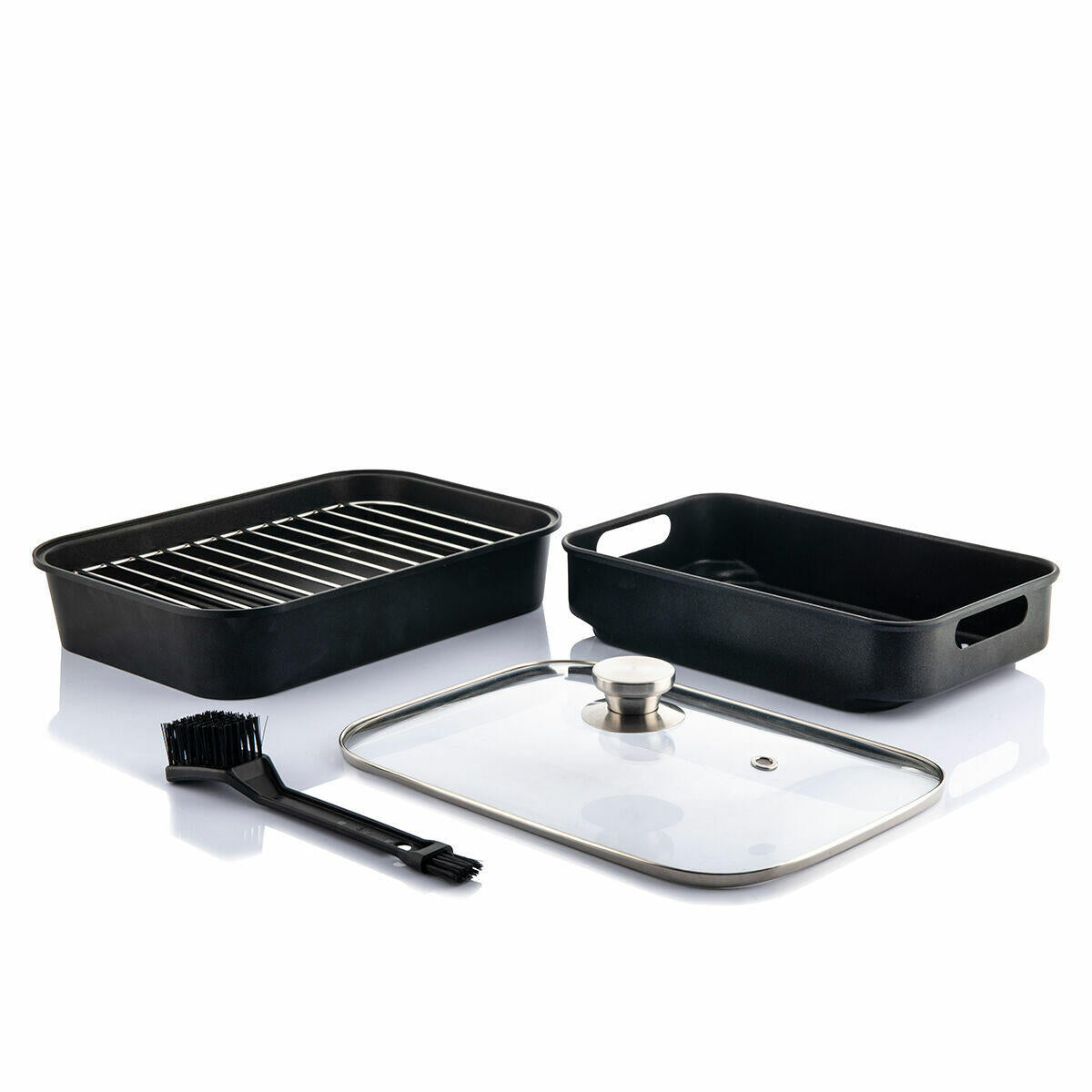 A black roasting pan set with a metal rack, a glass lid with a metal handle, and a black basting brush, all displayed on a white surface.