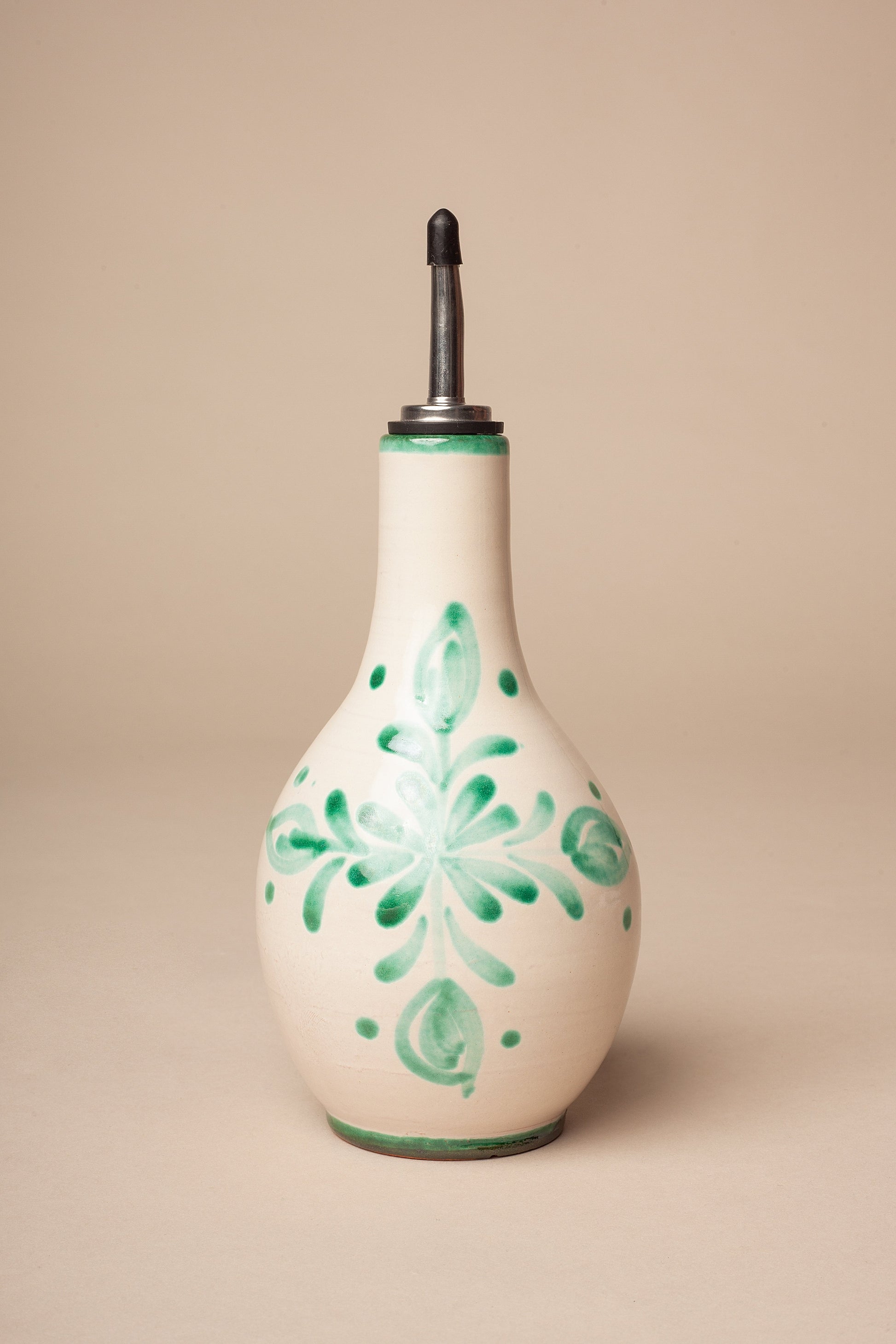 Botella aceitera de cerámica blanca con detalles verdes y tapa de metal, estilo artesanal decorativo.