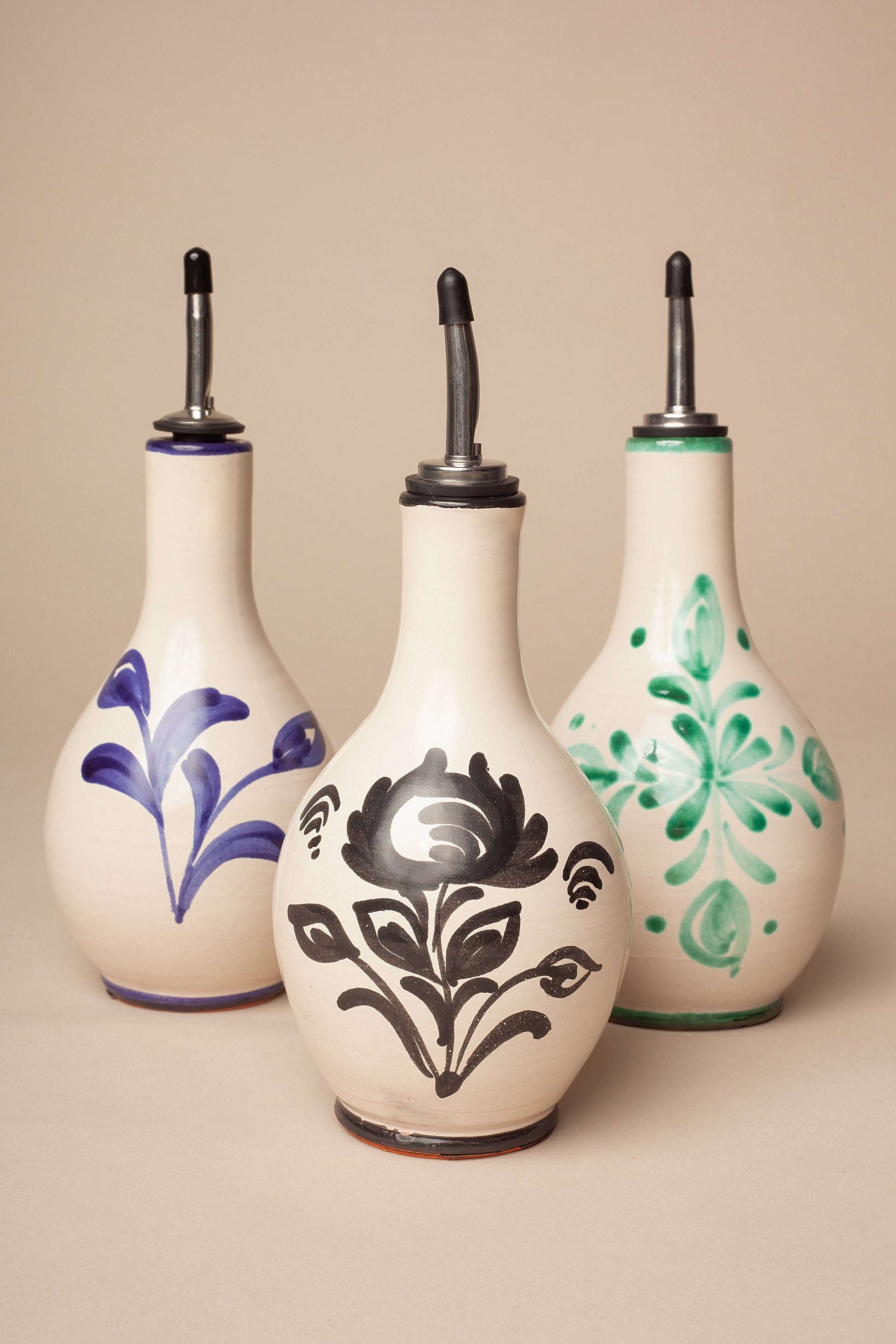 Botellas de cerámica decorativas en tonos blanco, azul y verde, con diseños florales y tapa de metal.
