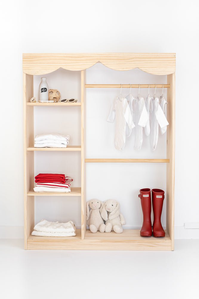 Armario de madera clara con estantes y perchas, incluye ropa blanca y roja, y botas rojas. Ideal para niños.
