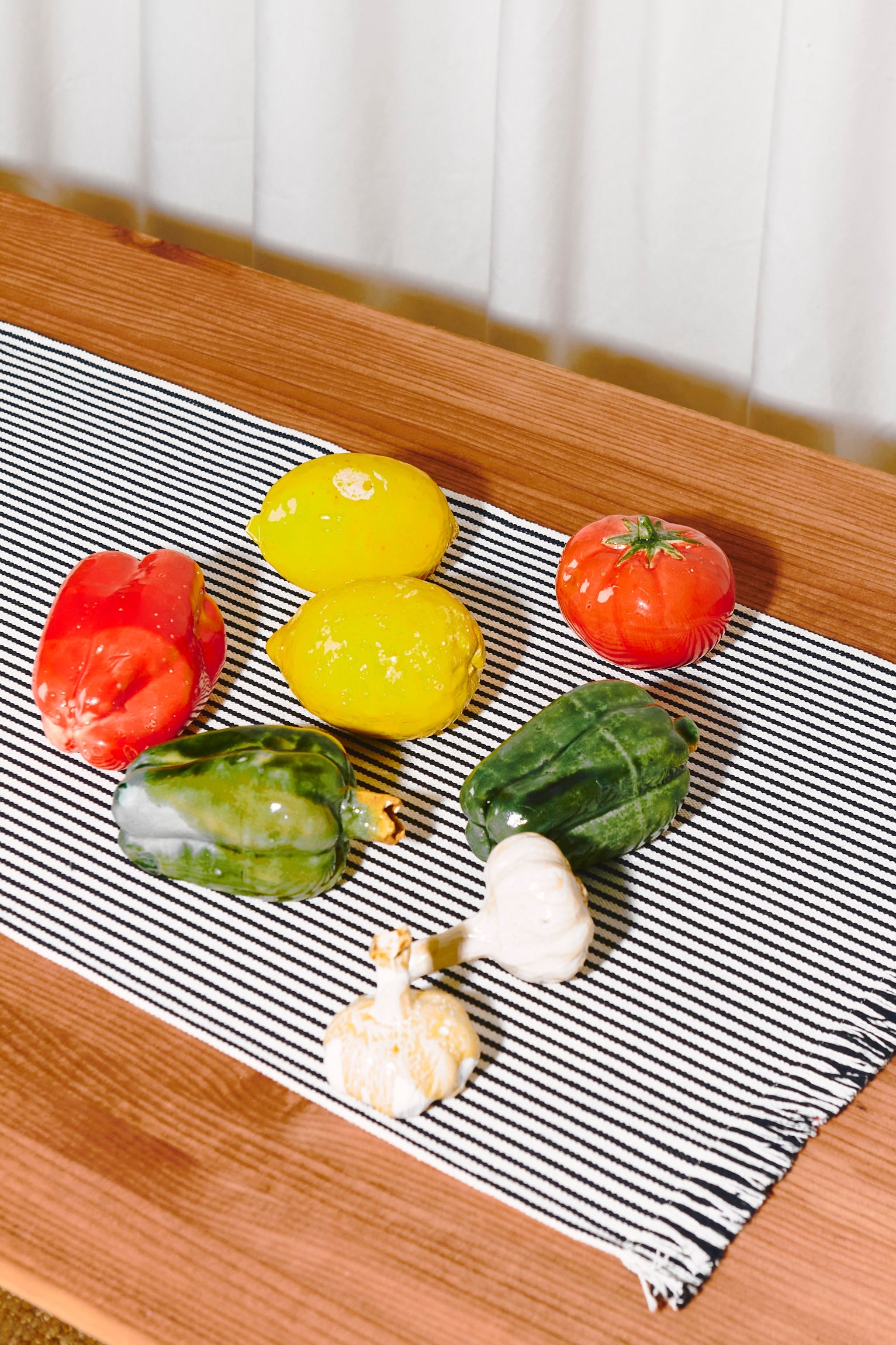 Verduras frescas y colores vibrantes sobre un mantel a rayas, incluye pimientos, tomates y limones.