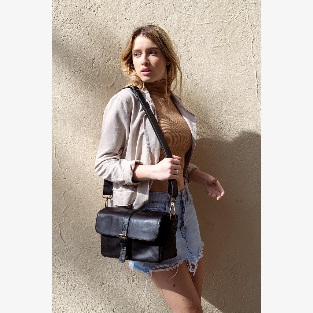 Paris black leather camera bag displayed on wooden surface with accessories