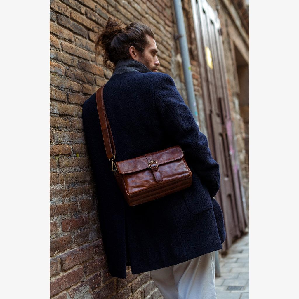 Handmade leather camera bag worn by a man in a stylish setting, showcasing elegance and craftsmanship.
