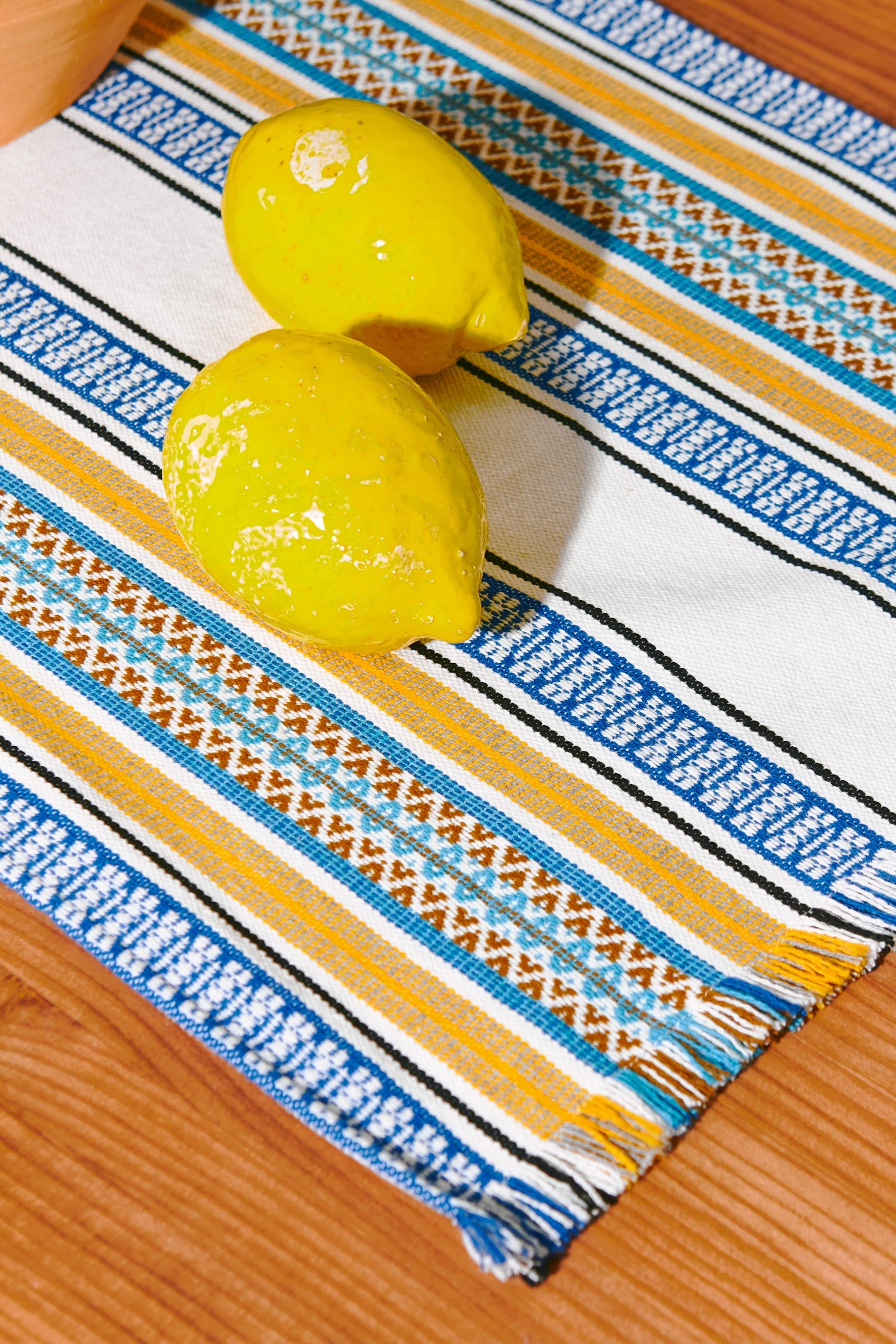 Manta de mesa de algodón blanco, azul y amarillo con diseño en rayas, decorada con limones.