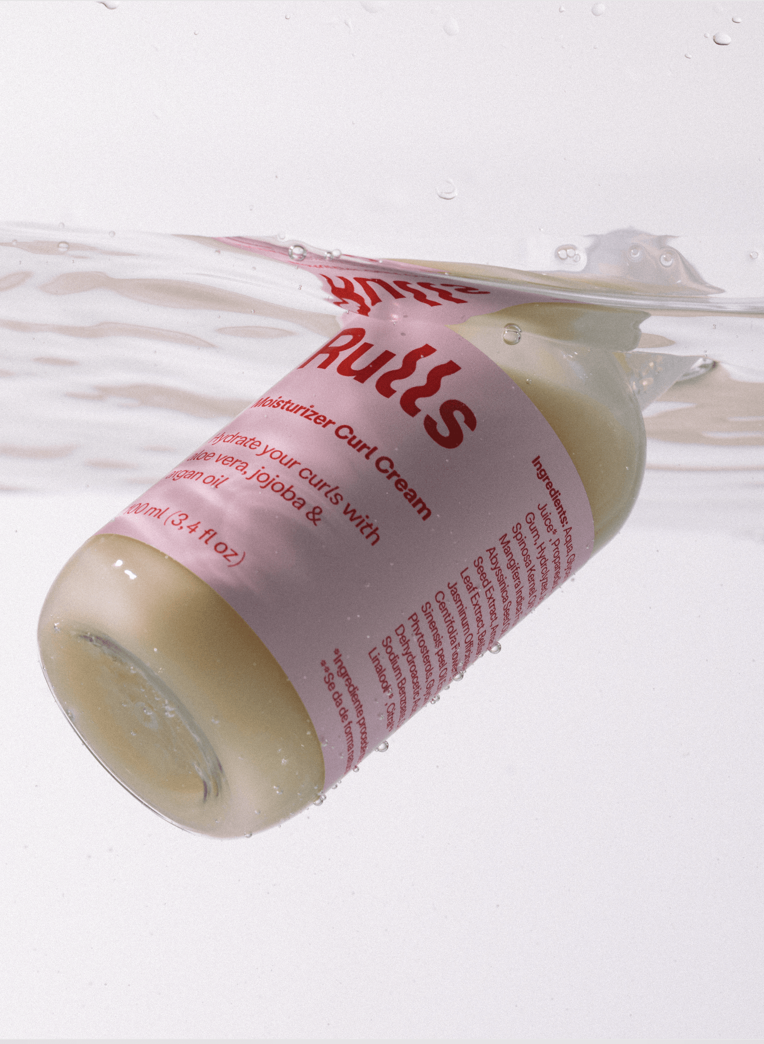 Crema para rizos en botella transparente, color rosa claro, fórmula hidratante con aloe vera y jojoba, 100 ml.