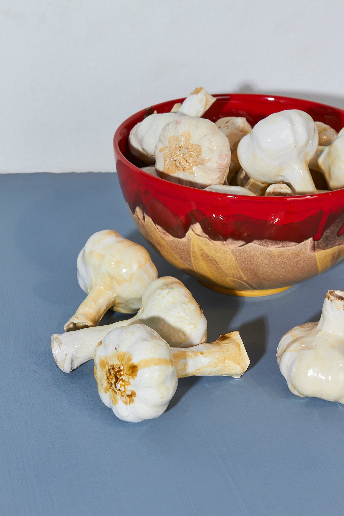 Ajo blanco en tazón de cerámica roja brillante, fondo azul claro, estilo moderno y artesanal.