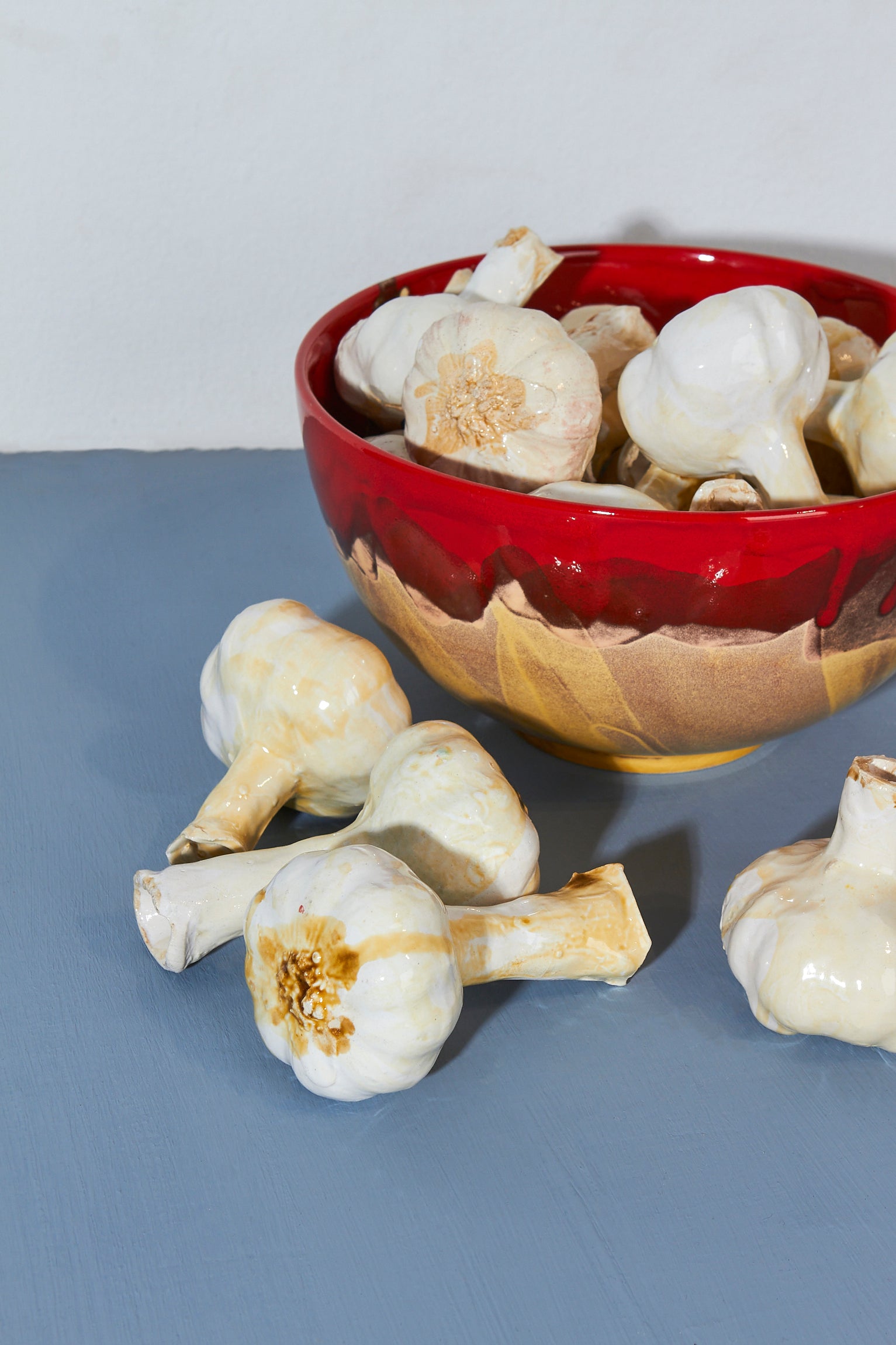 Ajo blanco en tazón de cerámica roja brillante, fondo azul claro, estilo moderno y artesanal.