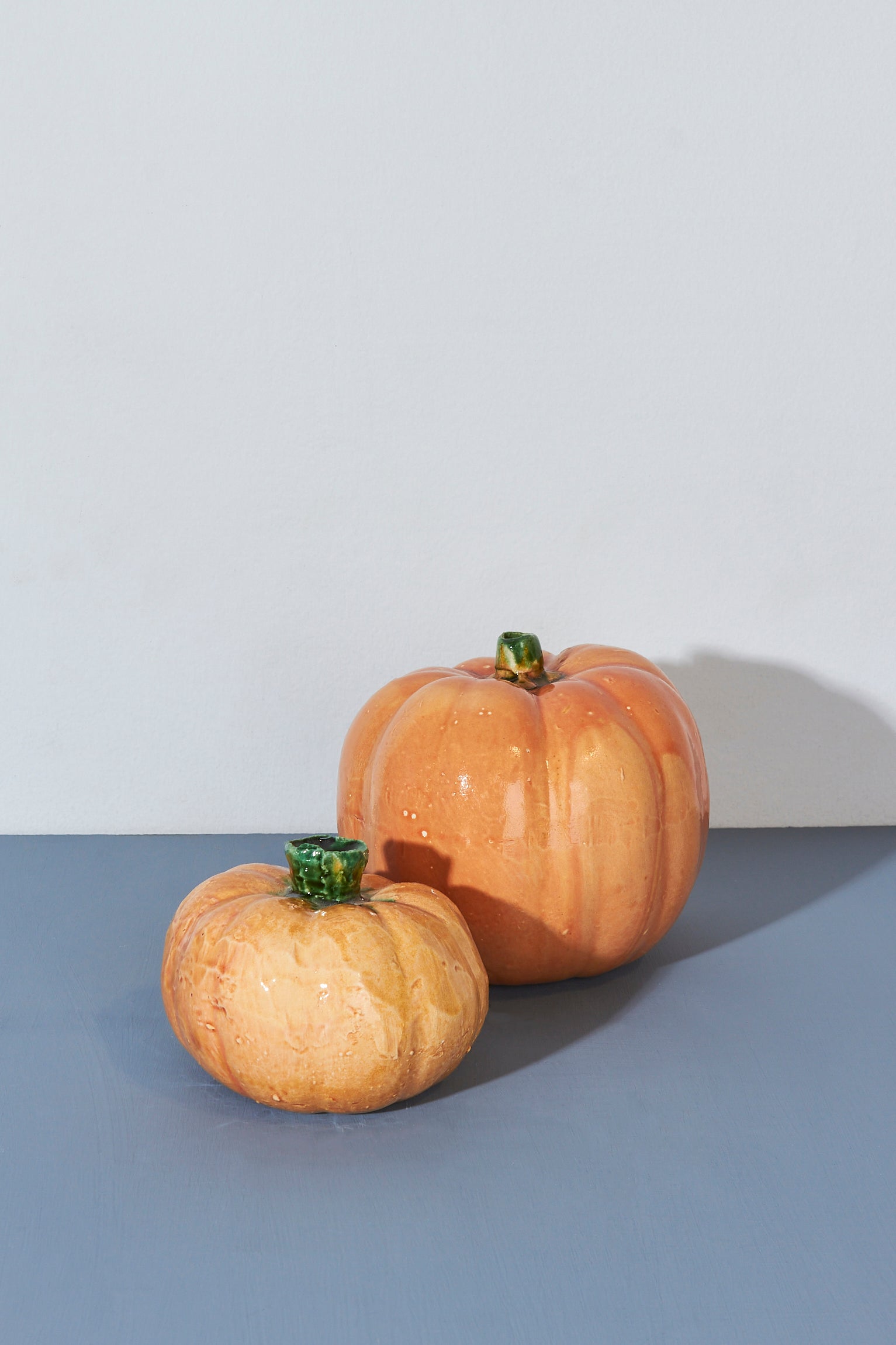 Calabazas decorativas de cerámica en tonos naranjas y verdes, ideales para adornos de otoño.