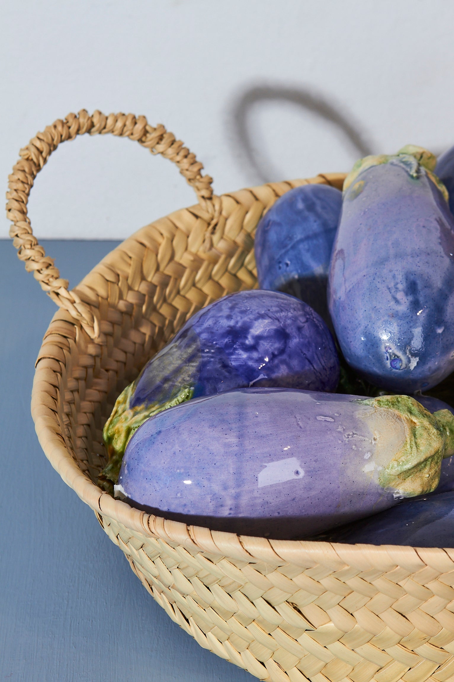 Cesta de mimbre con berenjenas moradas brillantes, estilo rústico y artesanal, ideal para decoración.
