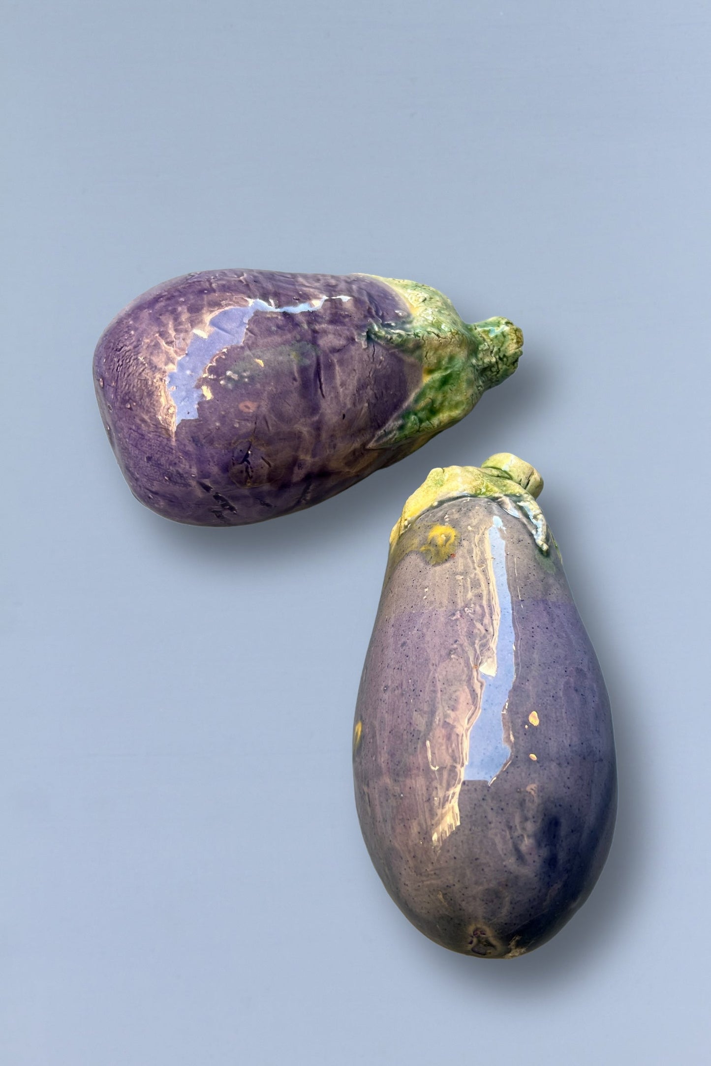 Berenjenas moradas brillantes, frescas y carnosas, ideales para cocinar o ensaladas, sobre fondo gris claro.