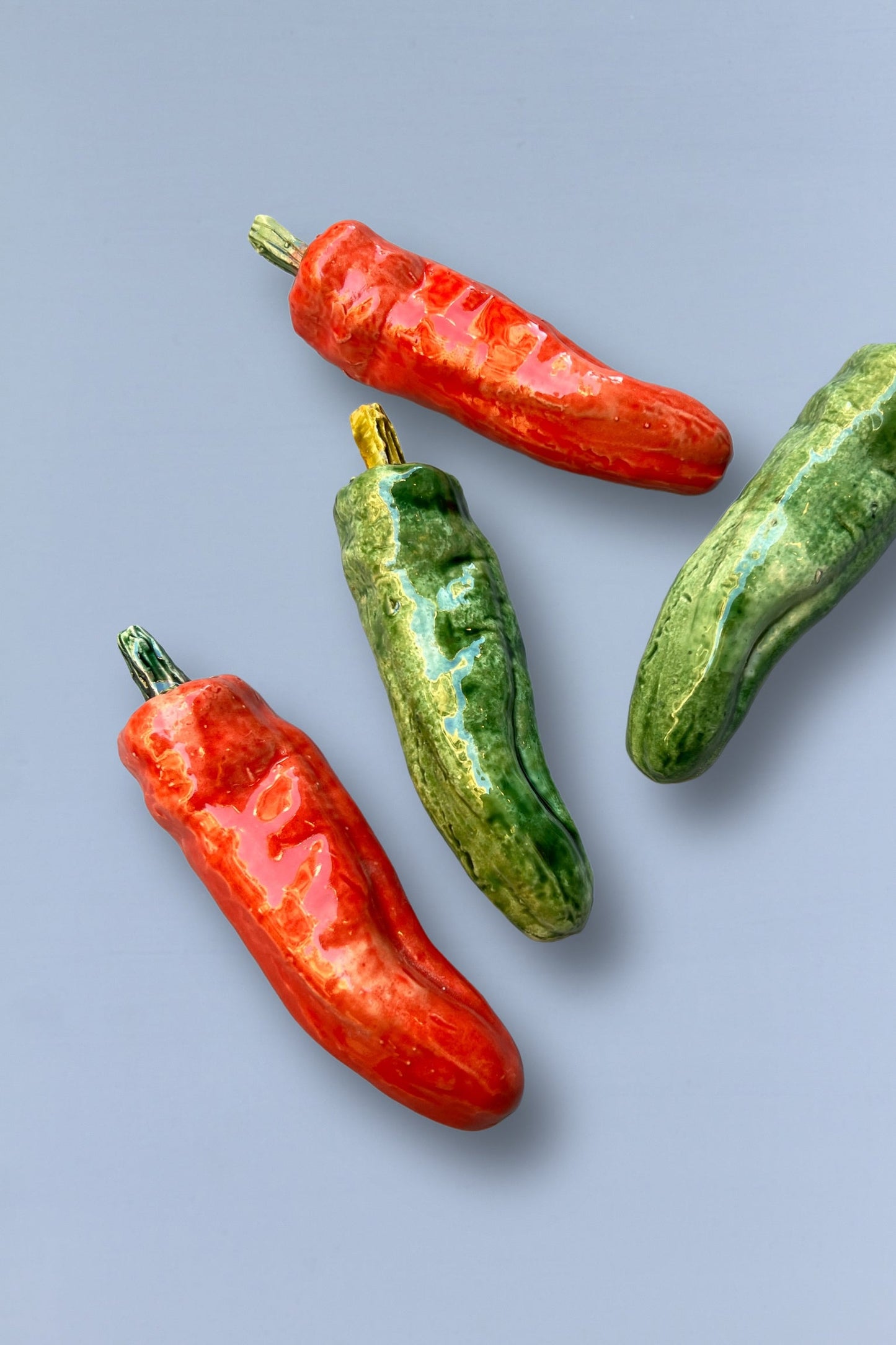 Pimientos de cerámica verde y rojo, decorativos, estilo artesanal, brillantes y vibrantes, ideales para cocina.