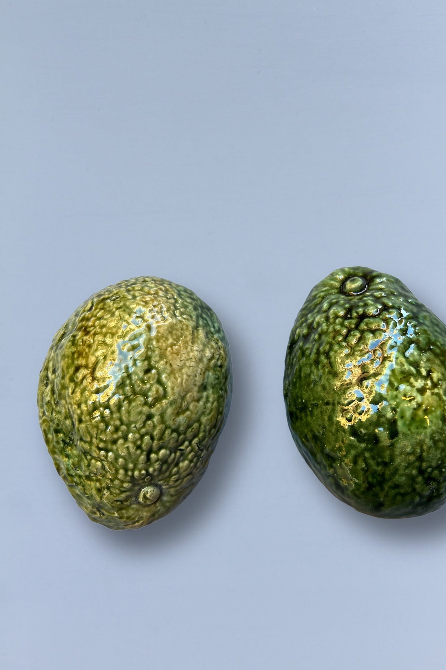 Aguacates de cerámica verde brillante, textura realista, ideal para decoración moderna de cocina.