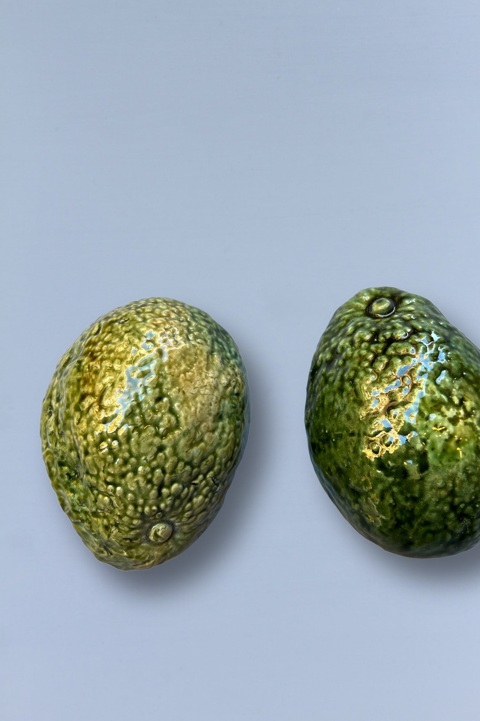 Aguacates de cerámica verde brillante, textura realista, ideal para decoración moderna de cocina.