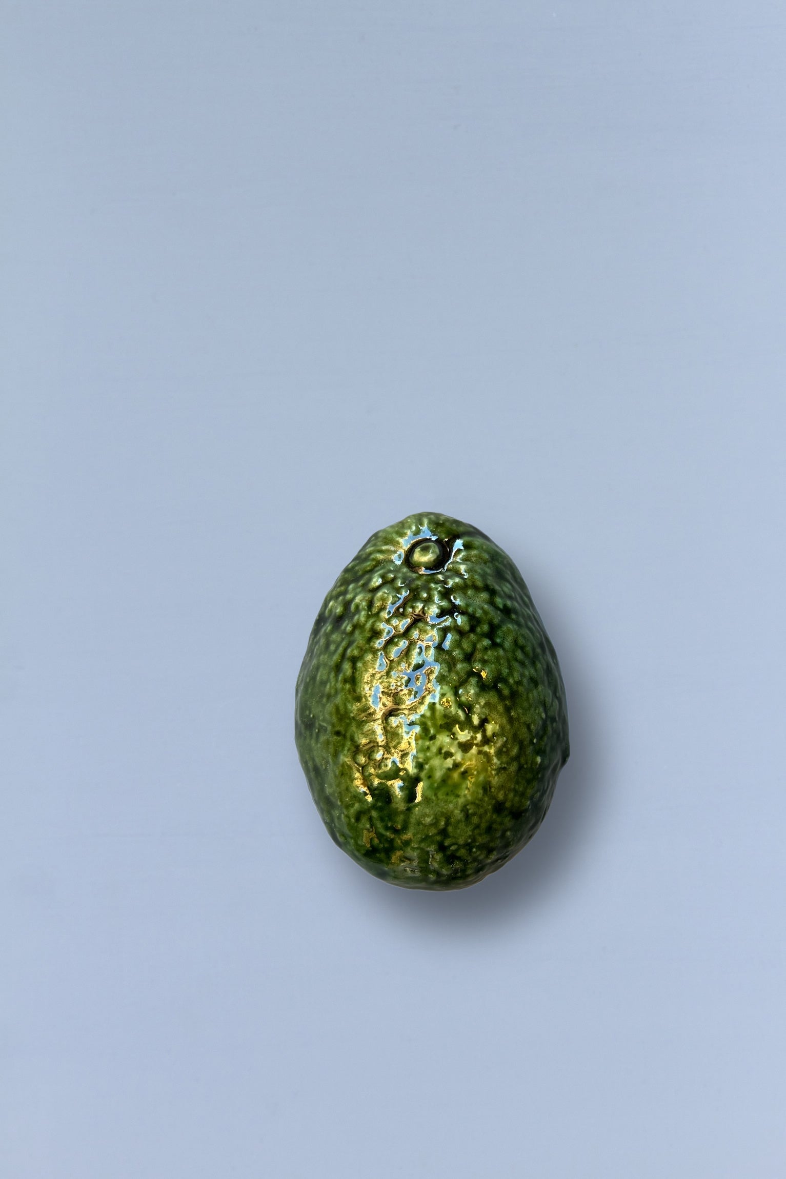 Aguacate de cerámica verde brillante, estilo moderno, ideal como decoración o utensilio de cocina.